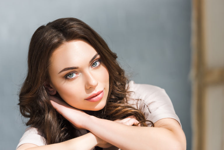 dreamy young and curly woman looking at camera